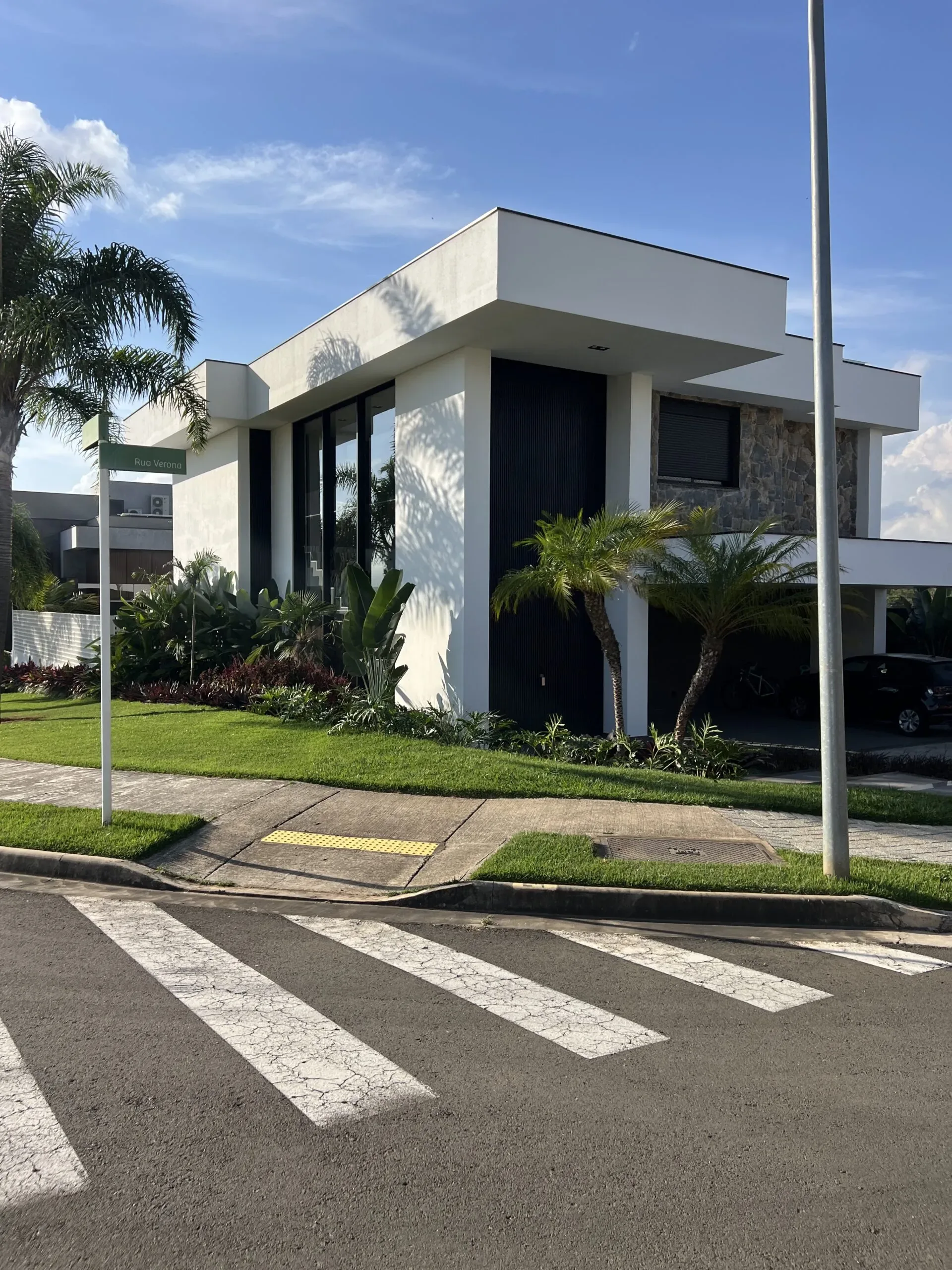 Casa de dois pavimentos com varanda superior protegida por brises verticais e guarda-corpo de vidro.